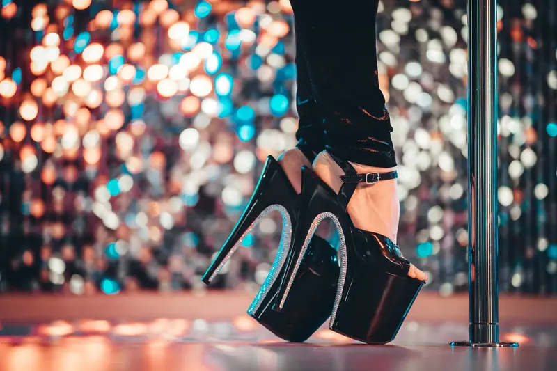 High Heels an der Polestange vor funkelndem Licht
